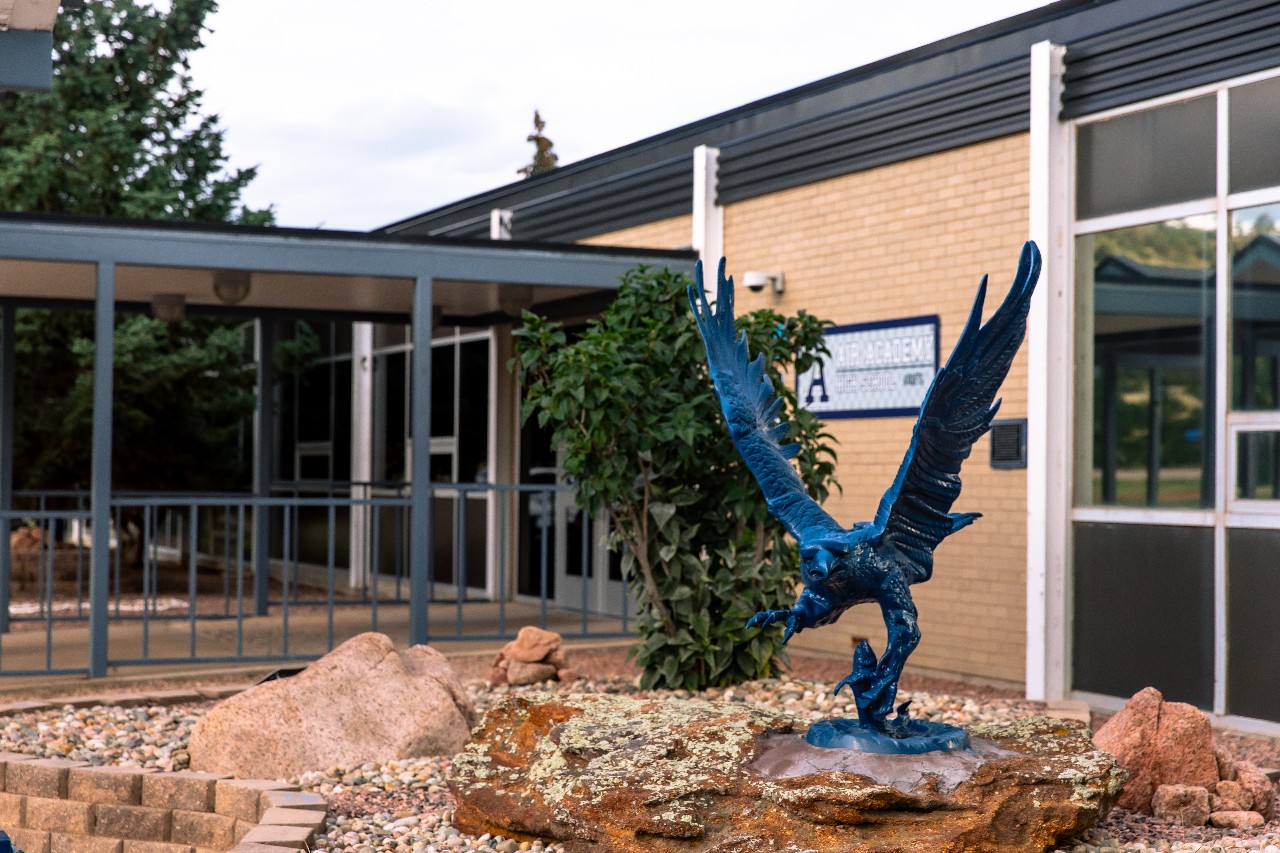 A blue metal sculpture stands outside the entrance to Air Academy High School.